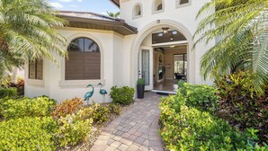 A house with a paved pathway, arched windows, and decorative bird sculptures. - • Sleeps 6 | 3 bedrooms |3 baths - Stars Vacation Rentals (Cape Coral)