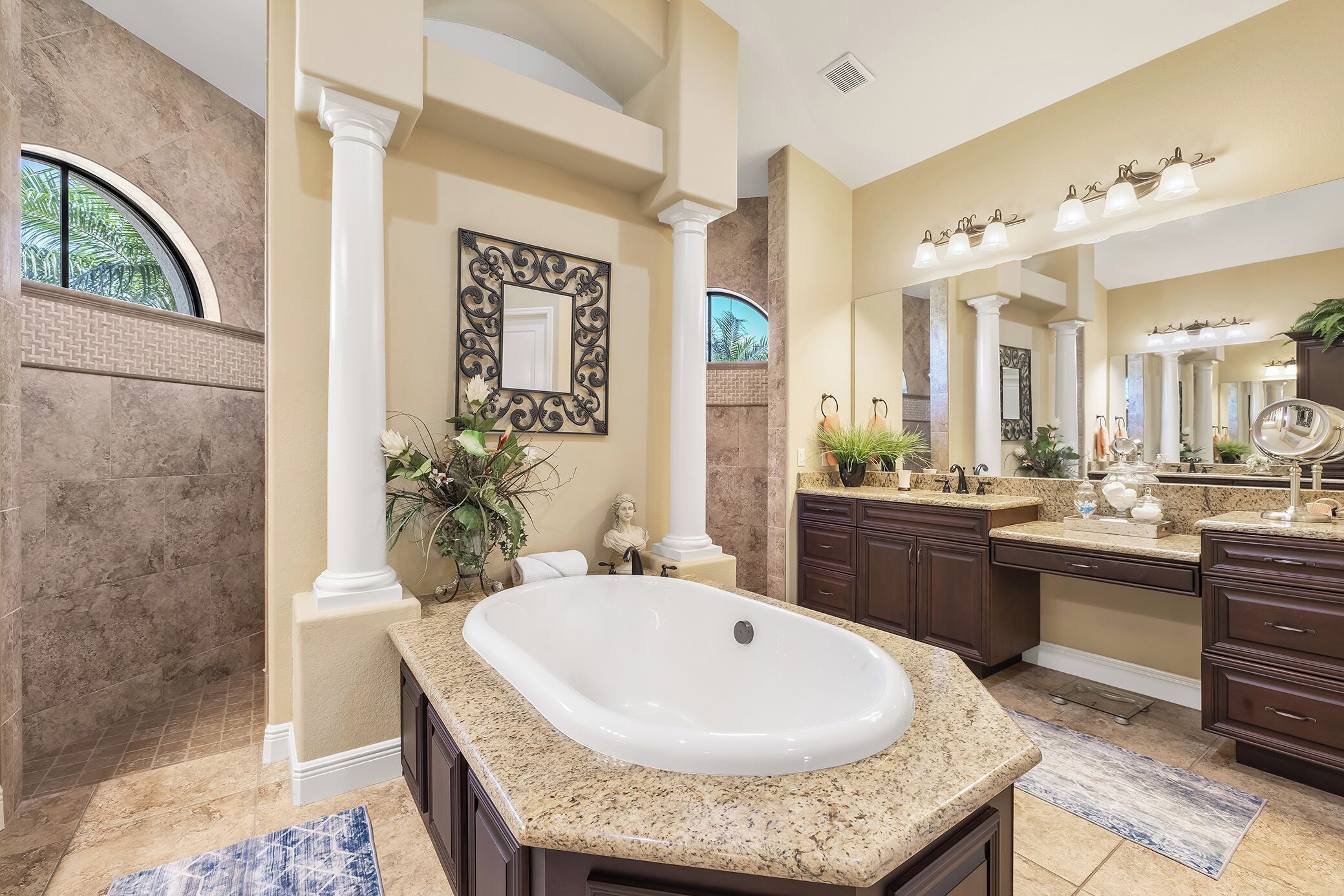 A spacious bathroom with a freestanding bathtub, marble countertops, and a large mirror.