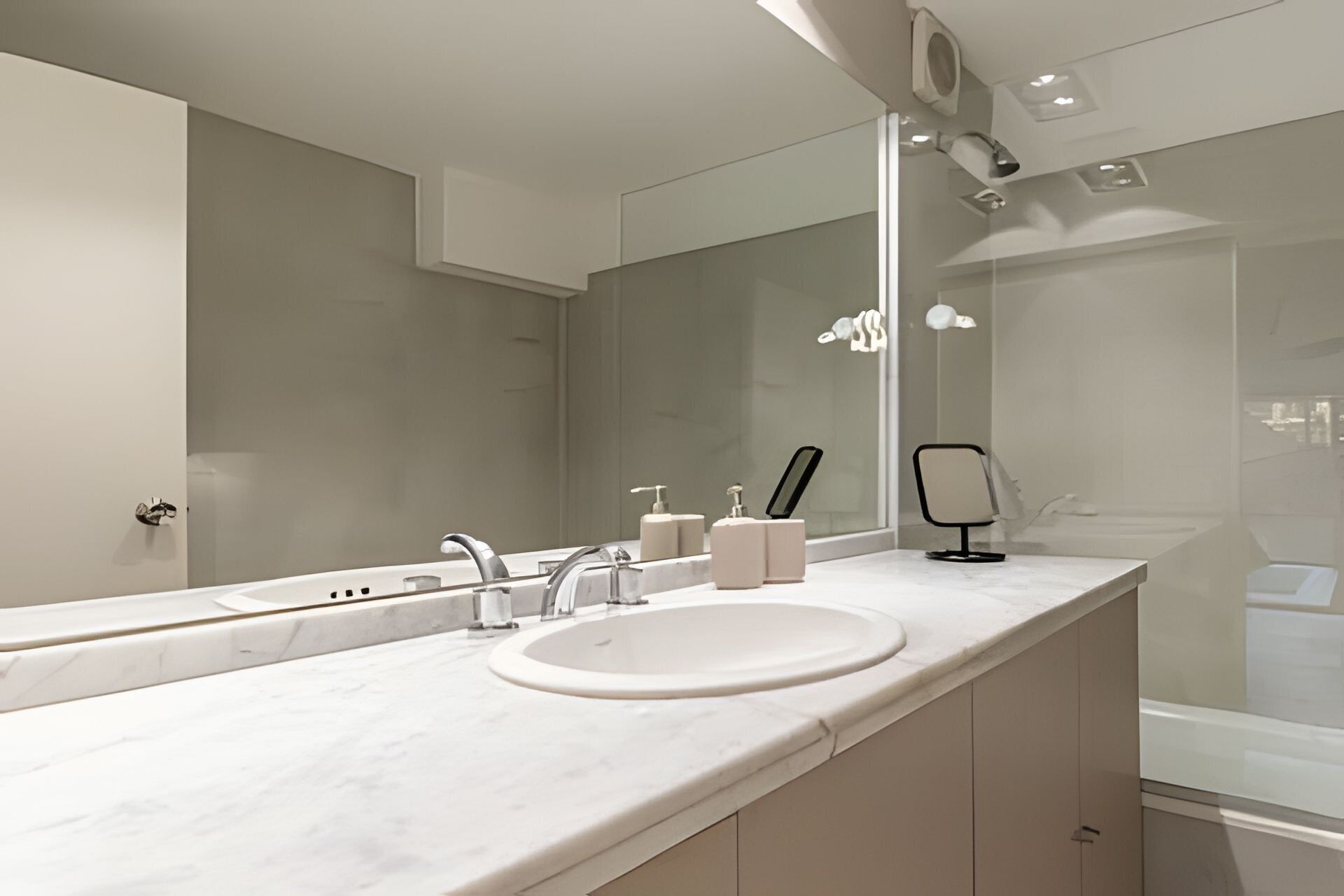 Een moderne badkamer met een grote spiegel, een wastafel en een douchehoek.