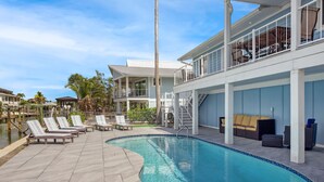 Une piscine avec des chaises longues, un escalier et un bâtiment doté de balcons.