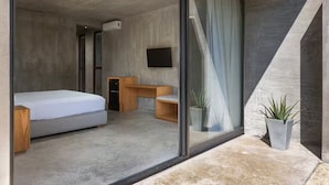 Ein modernes Schlafzimmer mit Bett, Schreibtisch und Fernseher.