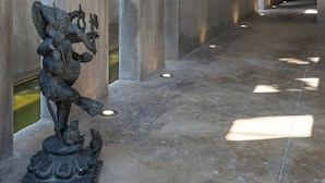 Ein Korridor mit hohen Säulen, einer Statue und einem Fliesenboden.