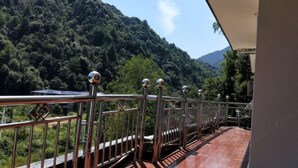 A balcony with a metal railing overlooking a mountainous landscape.