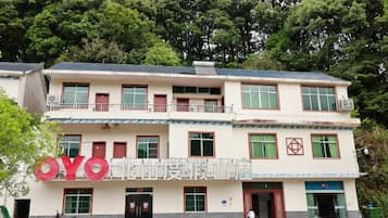 Edificio de dos pisos con un balcón en el nivel superior, una placa con las letras 'YO' en la fachada y una puerta con un letrero rojo encima.