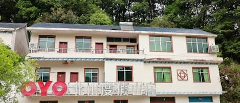 A two-story building with a balcony on the upper floor, a sign with the letters 'YO' on the facade, and a door with a red sign above it.