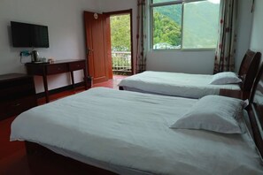 Une chambre d’hôtel avec deux lits, une télévision, un bureau et un balcon offrant une vue sur la montagne.