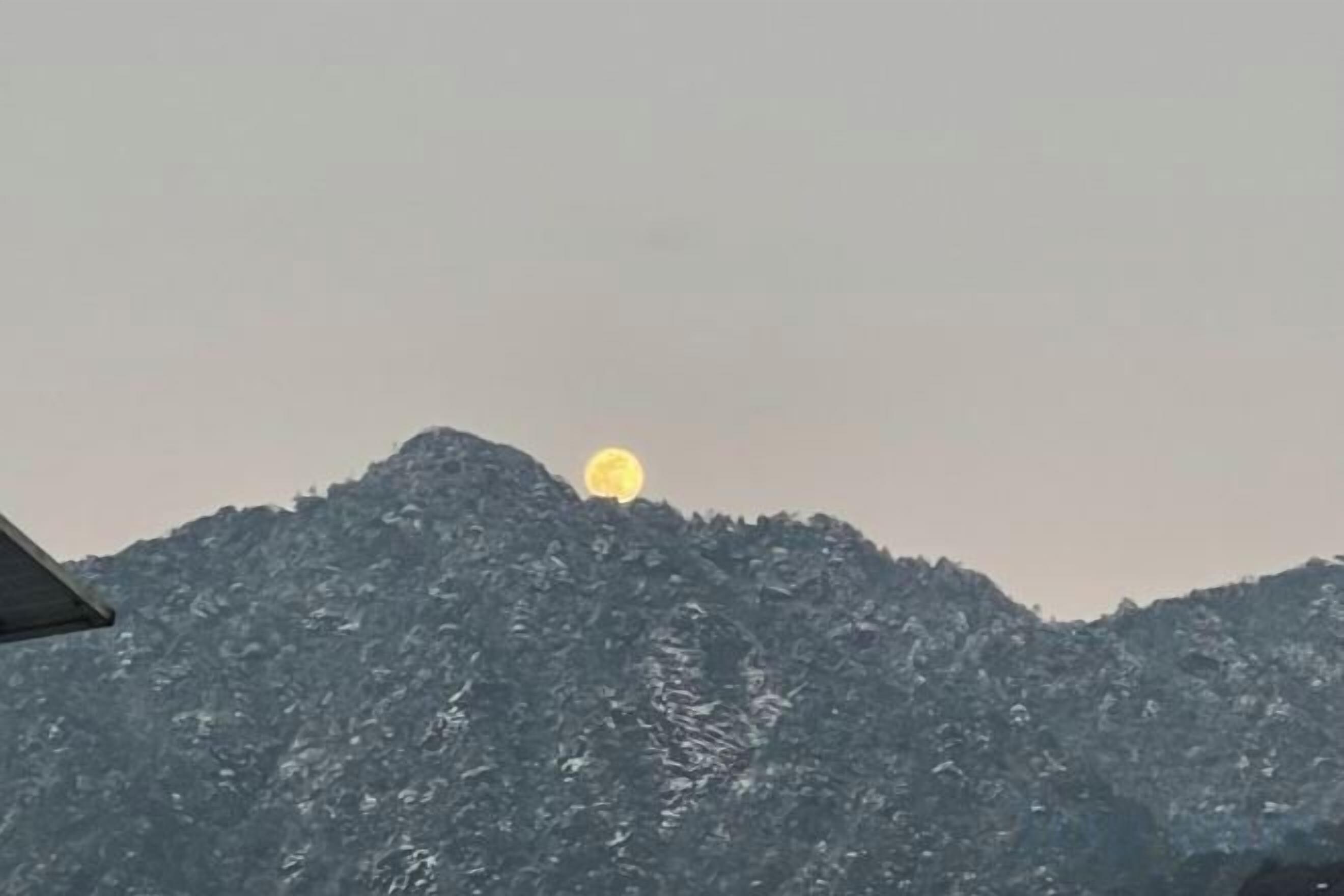 A mountain with a full moon in the sky.