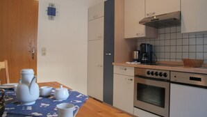 A compact kitchen with a stove, oven, and a coffee maker on the counter.