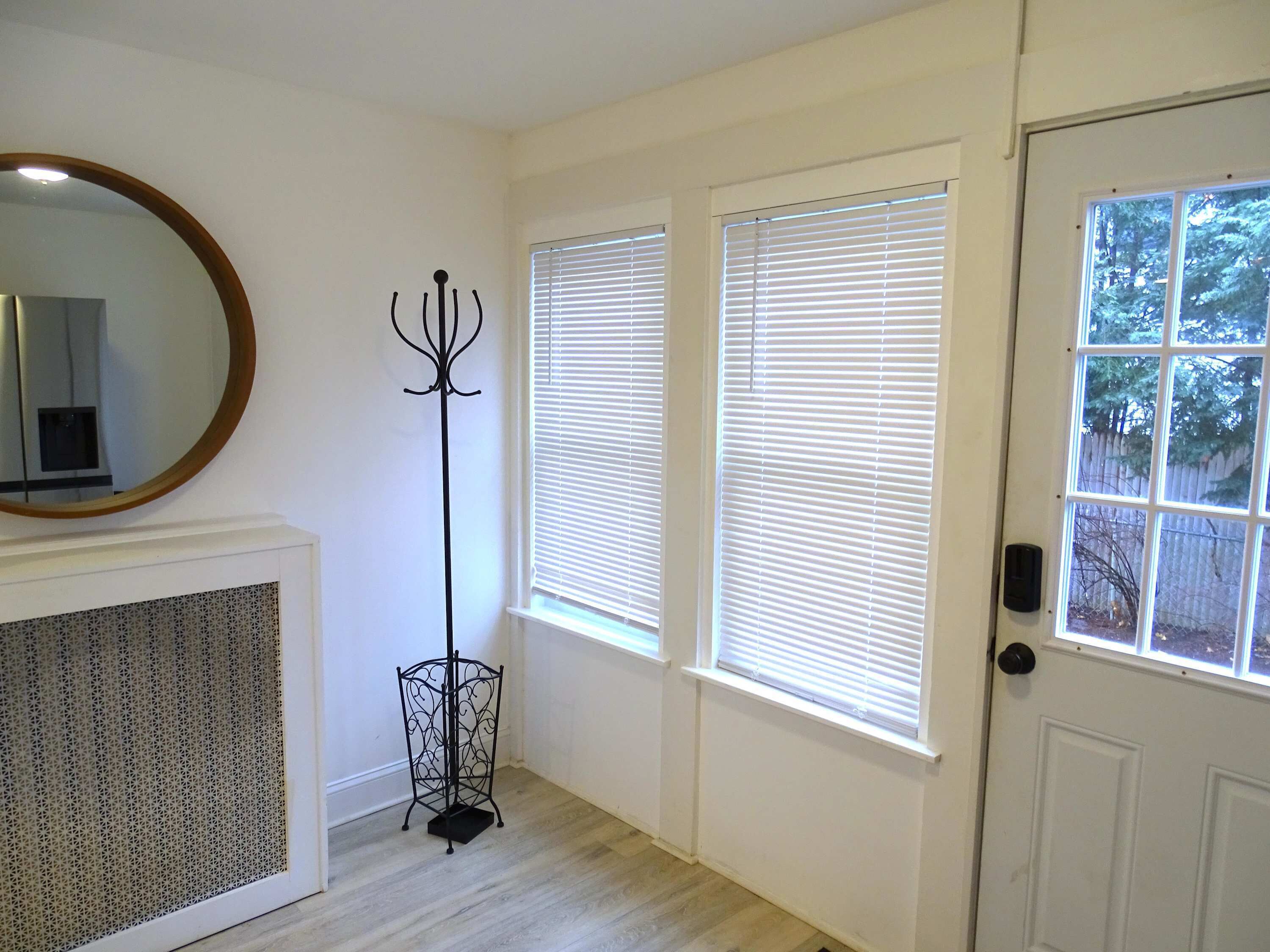 A hallway with a white door, a coat rack, and a radiator.
