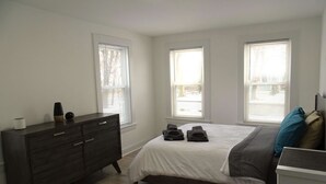 A bedroom with a bed, dresser, and windows. - Comfortable 3 Bed Apt in Quiet Neighborhood (Wayland)