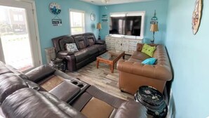 A living room with a brown leather sofa, a brown couch, a coffee table, and a ceiling fan. - 3-bedroom villa in charming North Topsail Beach with WiFi, AC  Ocean front view (North Topsail Beach)