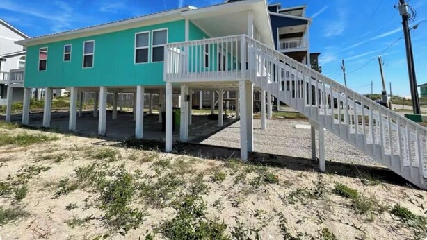A beachfront house with a covered patio and a staircase leading to a balcony. - 3-bedroom villa in charming North Topsail Beach with WiFi, AC  Ocean front view (North Topsail Beach)