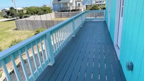 A blue deck with a white railing, overlooking a grassy yard and neighboring houses. - 3-bedroom villa in charming North Topsail Beach with WiFi, AC  Ocean front view (North Topsail Beach)
