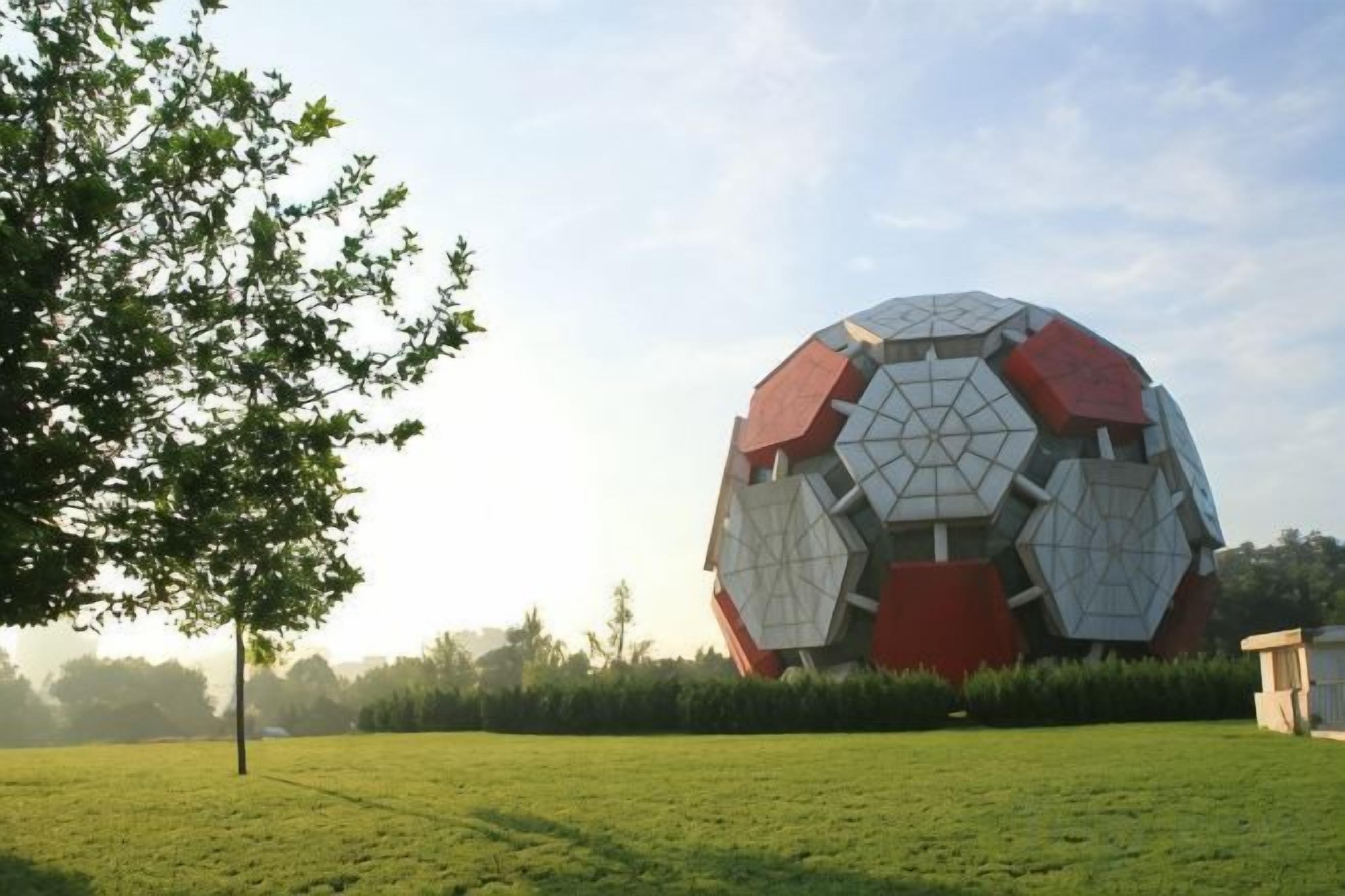 Una gran estructura esférica que recuerda a un balón de fútbol en un campo cubierto de hierba.