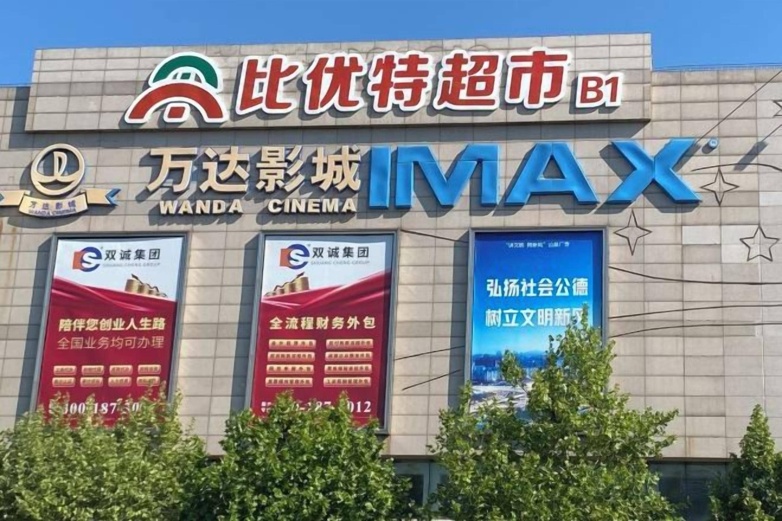 A cinema with the name 'Wanda Cinema' and 'IMAX' branding, featuring multiple movie posters and advertisements.