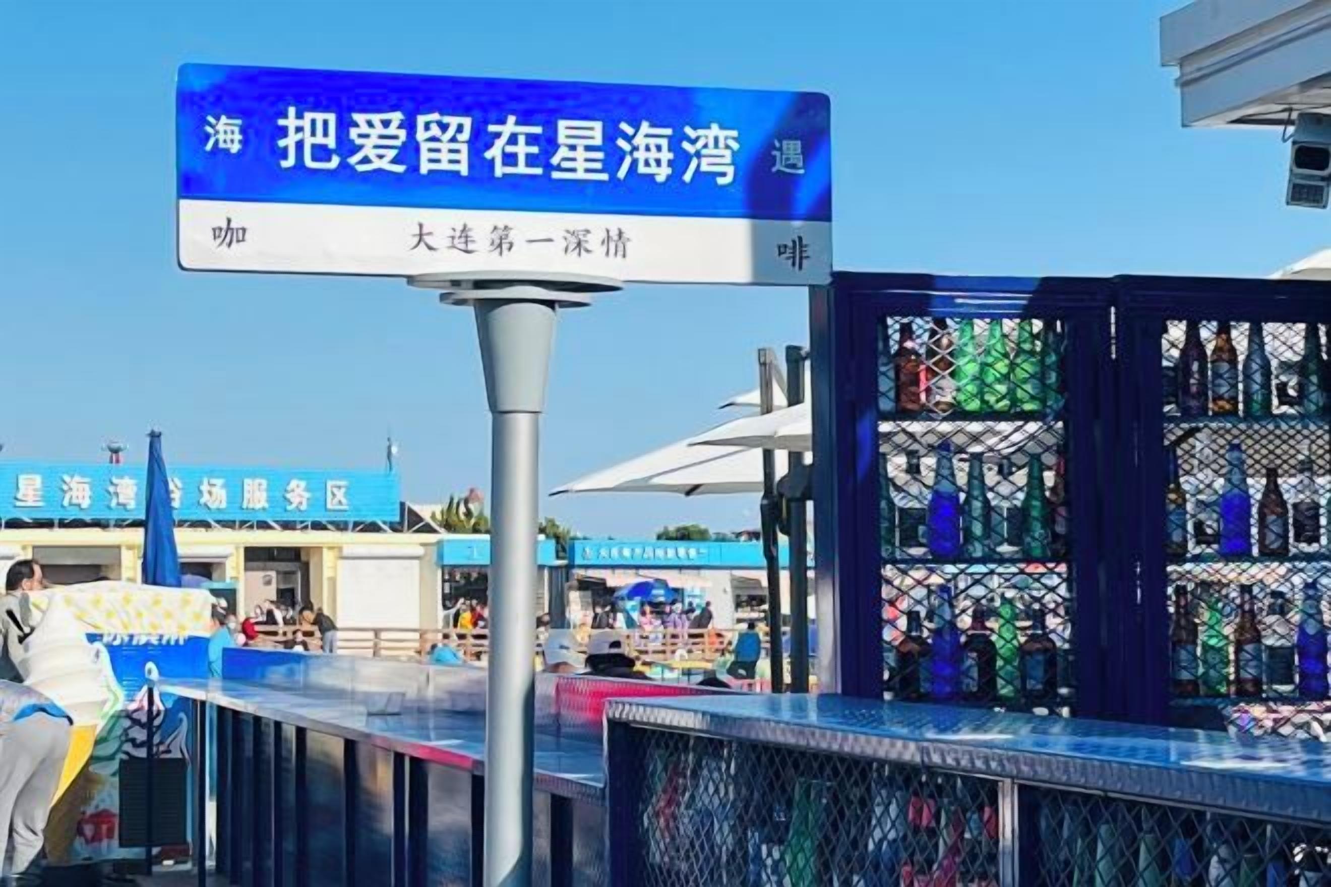 A sign with Chinese characters, a bar area with bottles, and a building with a blue sign in the background.