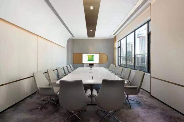 A conference room with a long table, multiple chairs, a large screen, and a city view through large windows. - City Boutique Hotel(Dalian Railway Station People Saunare Subway Branch (Dalian)
