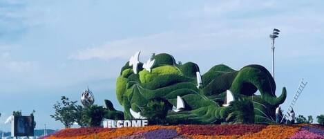 Uma grande escultura em forma de elefante, verde, com uma placa que diz 'WELCOME'.