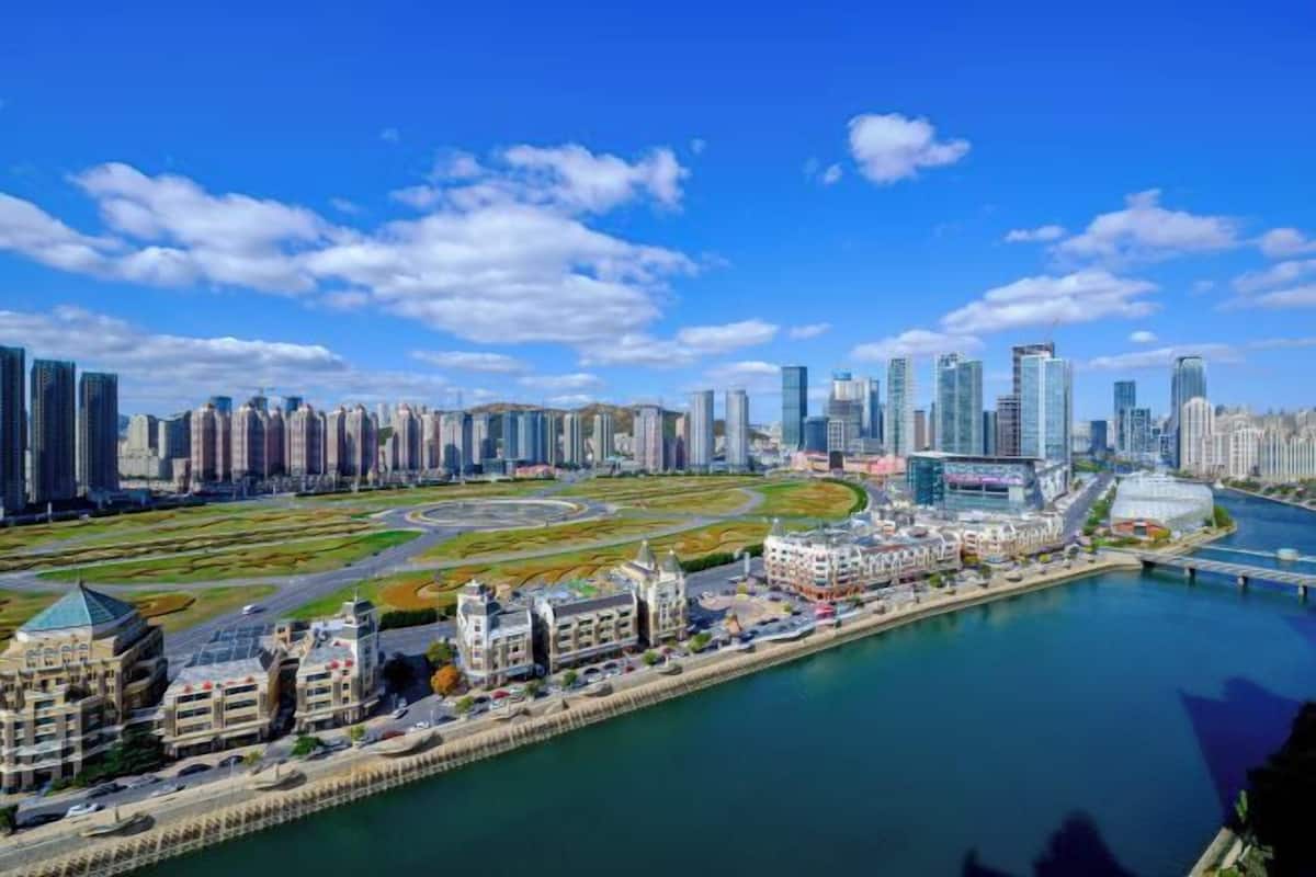 A cityscape with modern high-rise buildings, a waterfront promenade, and a central roundabout.