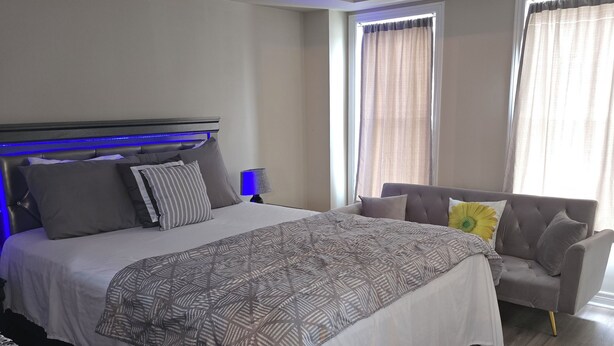 Une chambre à coucher moderne avec un grand lit, des tables de chevet, un canapé et un bureau avec une lampe.