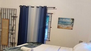 Une chambre à coucher avec un lit, une fenêtre avec des rideaux, un tableau au mur et un portail en métal.