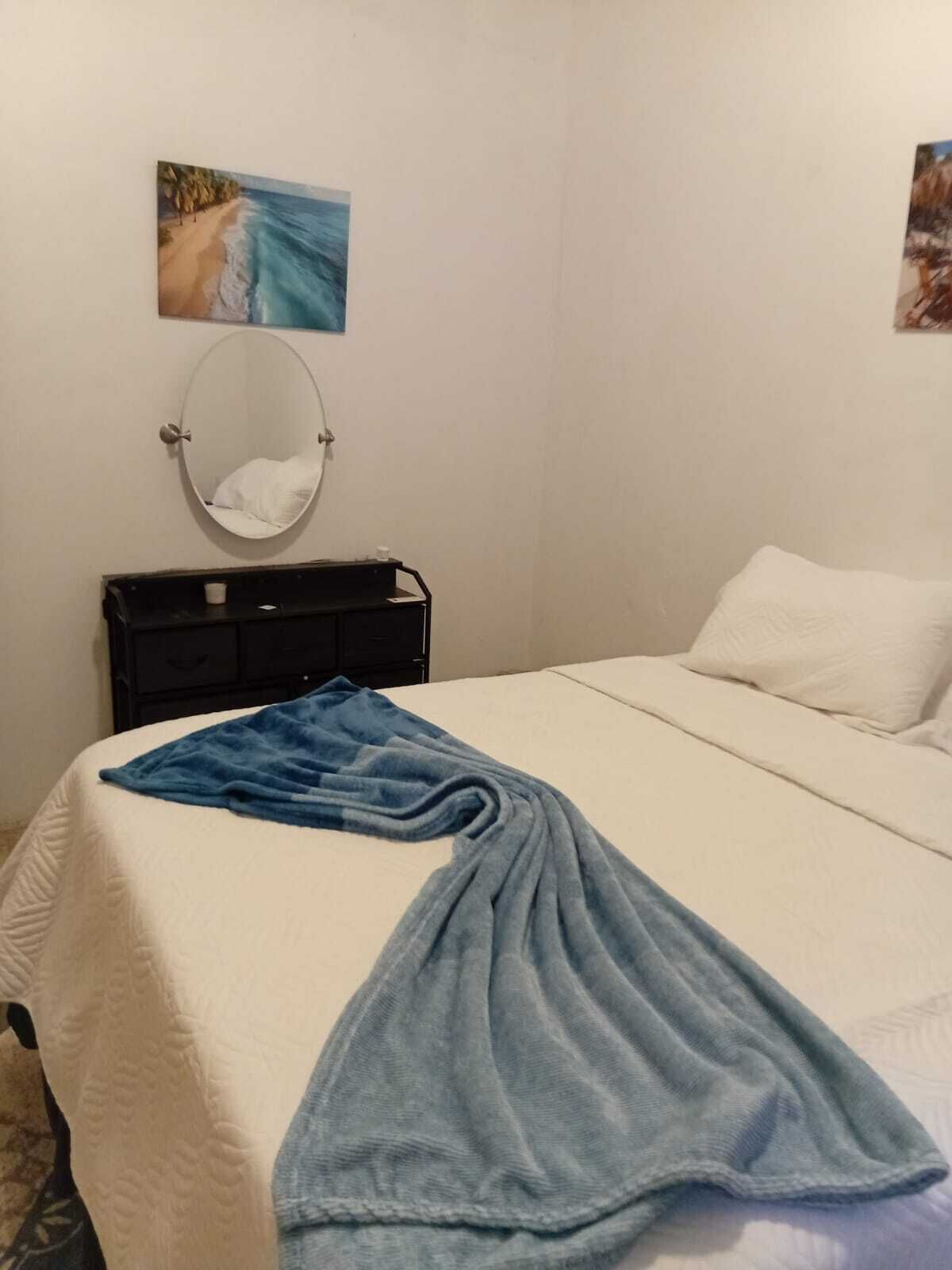 Una camera da letto con un letto, un comodino, uno specchio e un quadro appeso al muro.