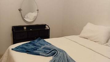 Una camera da letto con un letto, un comodino, uno specchio e un quadro appeso al muro.