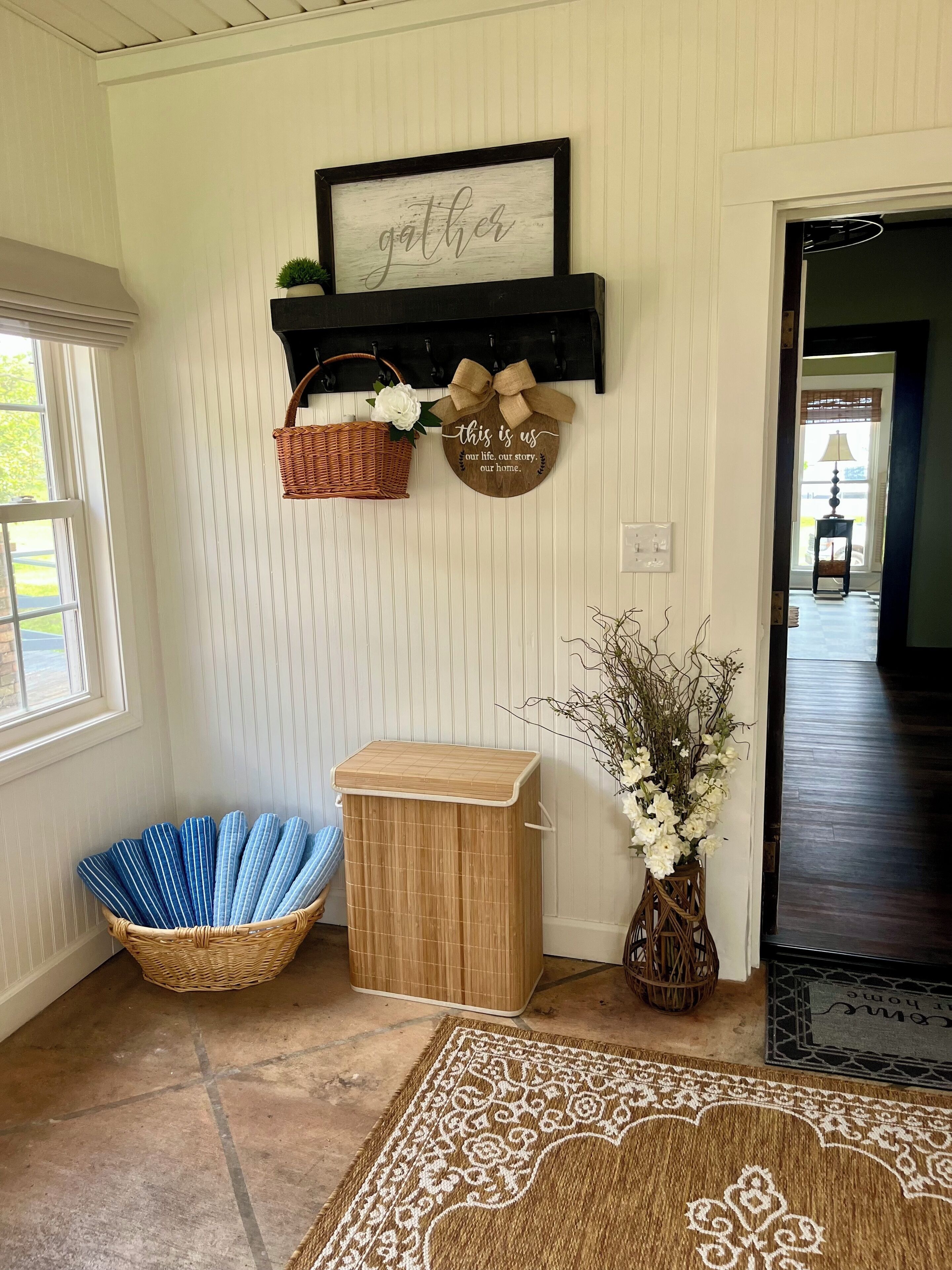 A hallway with a wooden bench, a wicker basket, a small wooden cabinet, and a decorative wall hanging.