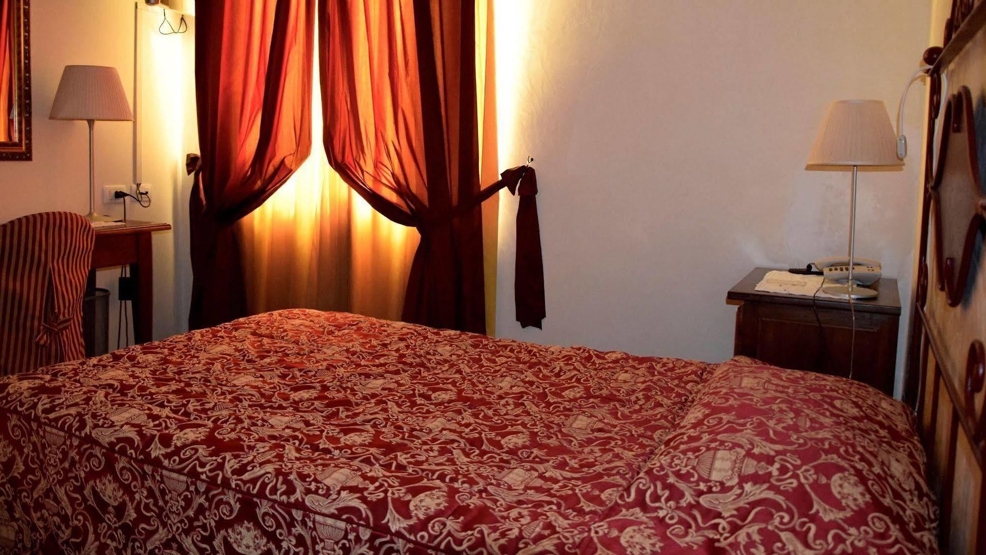A hotel room with a bed, a chair, a nightstand, and a lamp.