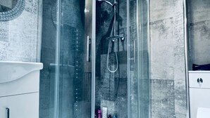A modern bathroom with a glass-enclosed shower, a white sink, and a marble-tiled wall. - Gateshead Gem - Modern 3 Bedroom House (Gateshead)