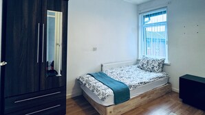 A bedroom with a bed, a wardrobe, a window, and a ceiling light. - Gateshead Gem - Modern 3 Bedroom House (Gateshead)