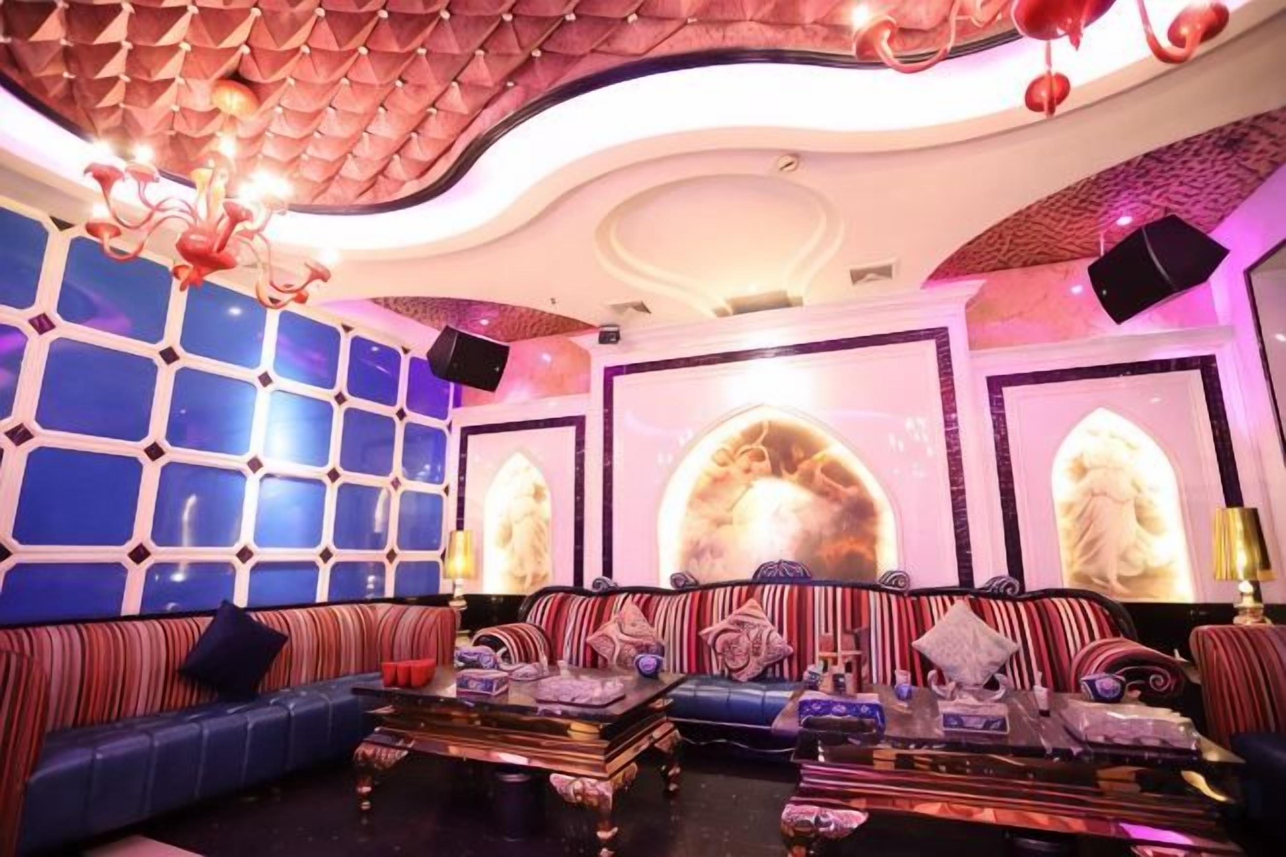 A luxurious lounge area with a patterned ceiling, plush seating, and decorative wall art.