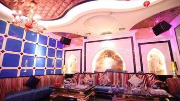 A luxurious lounge area with a patterned ceiling, plush seating, and decorative wall art.