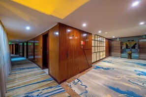 Un pasillo de hotel con paredes de madera, una alfombra estampada y una zona de recepción con mostrador.