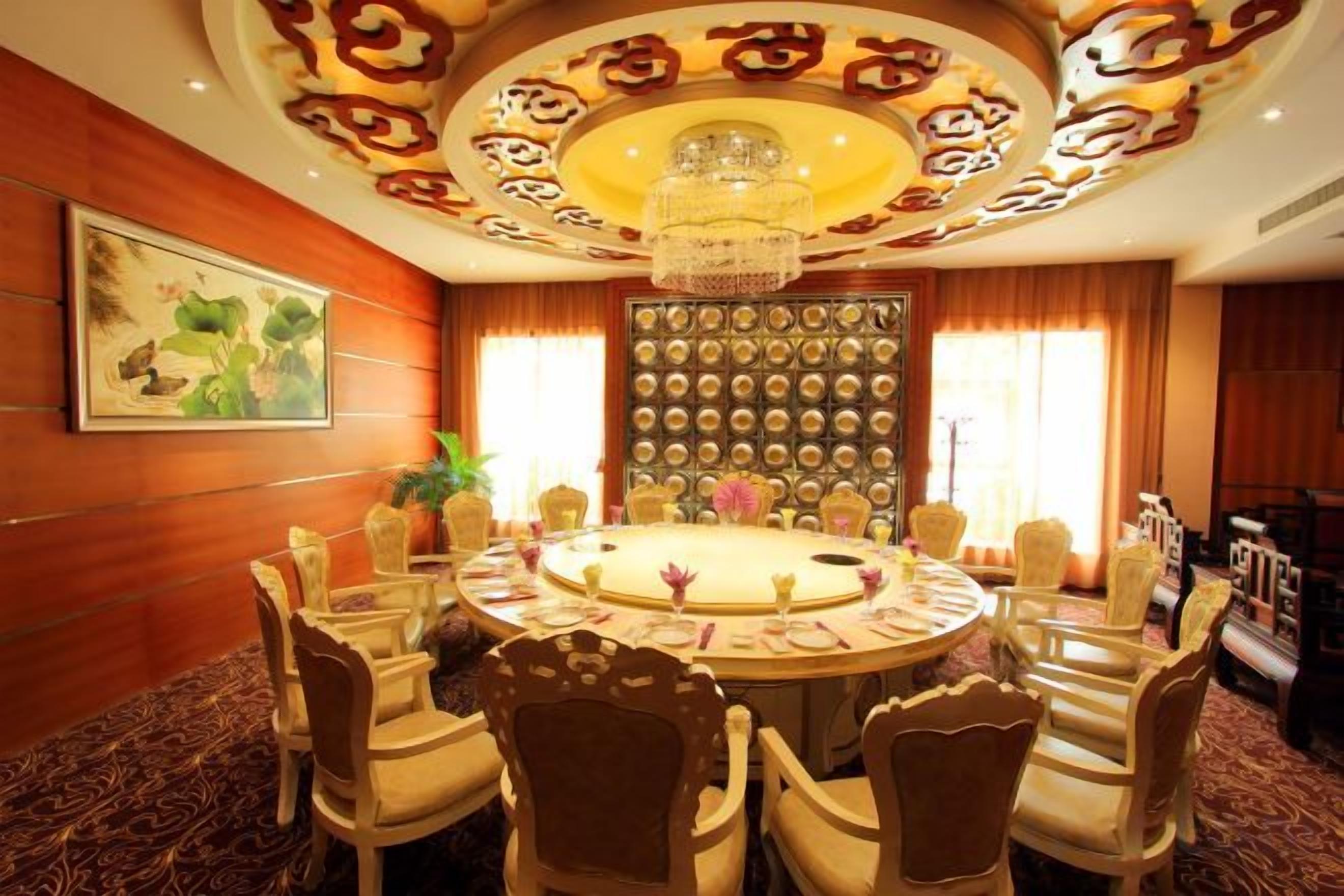 A conference room with a round table, chairs, and a decorative ceiling.