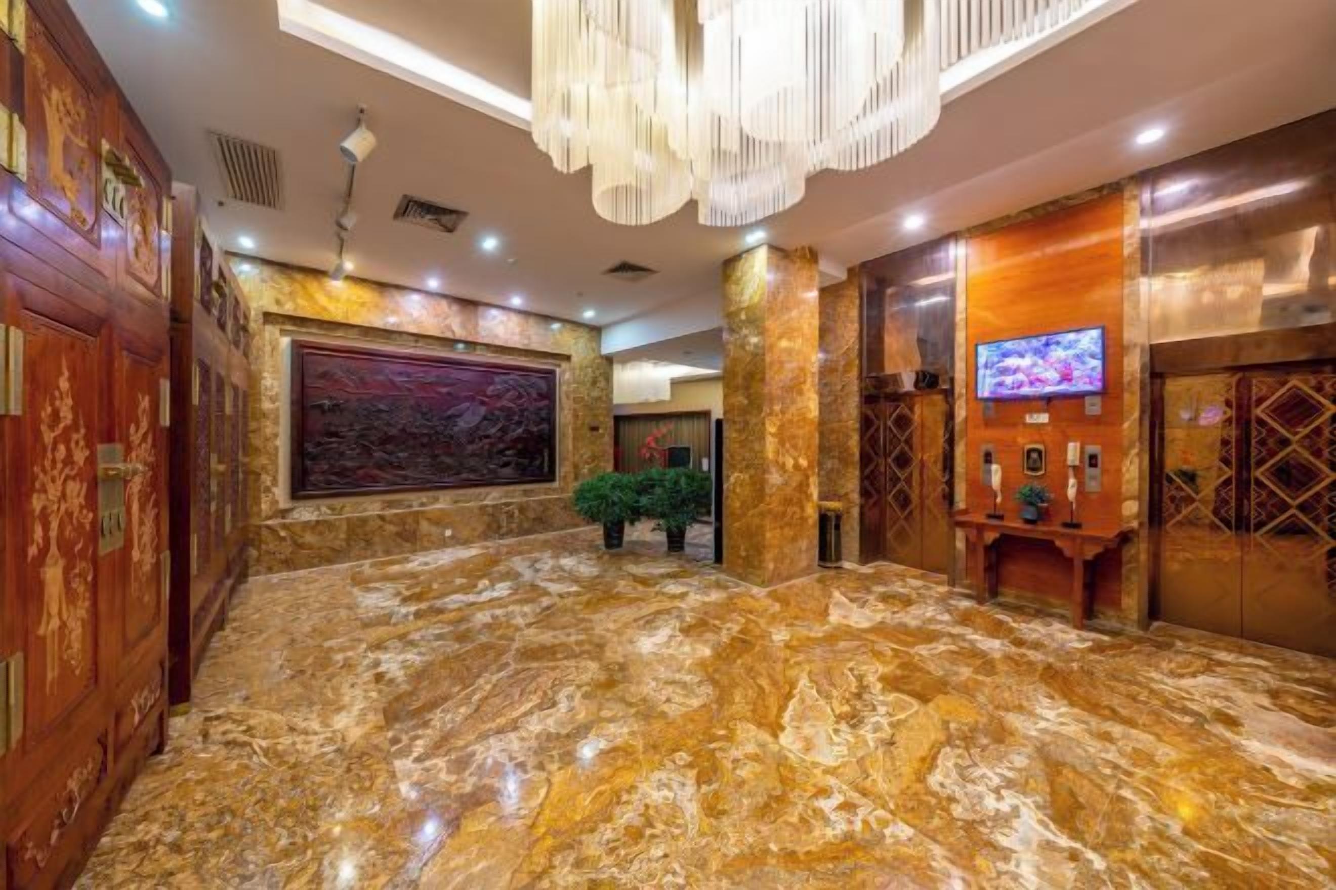 A lobby with a marble floor, a large painting, and a television screen.