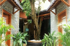 A courtyard with a large tree, potted plants, and a traditional building with wooden beams and brick walls. - Xixiangfeng International Hotel (Pingxiang Railway Station) (Pingxiang)