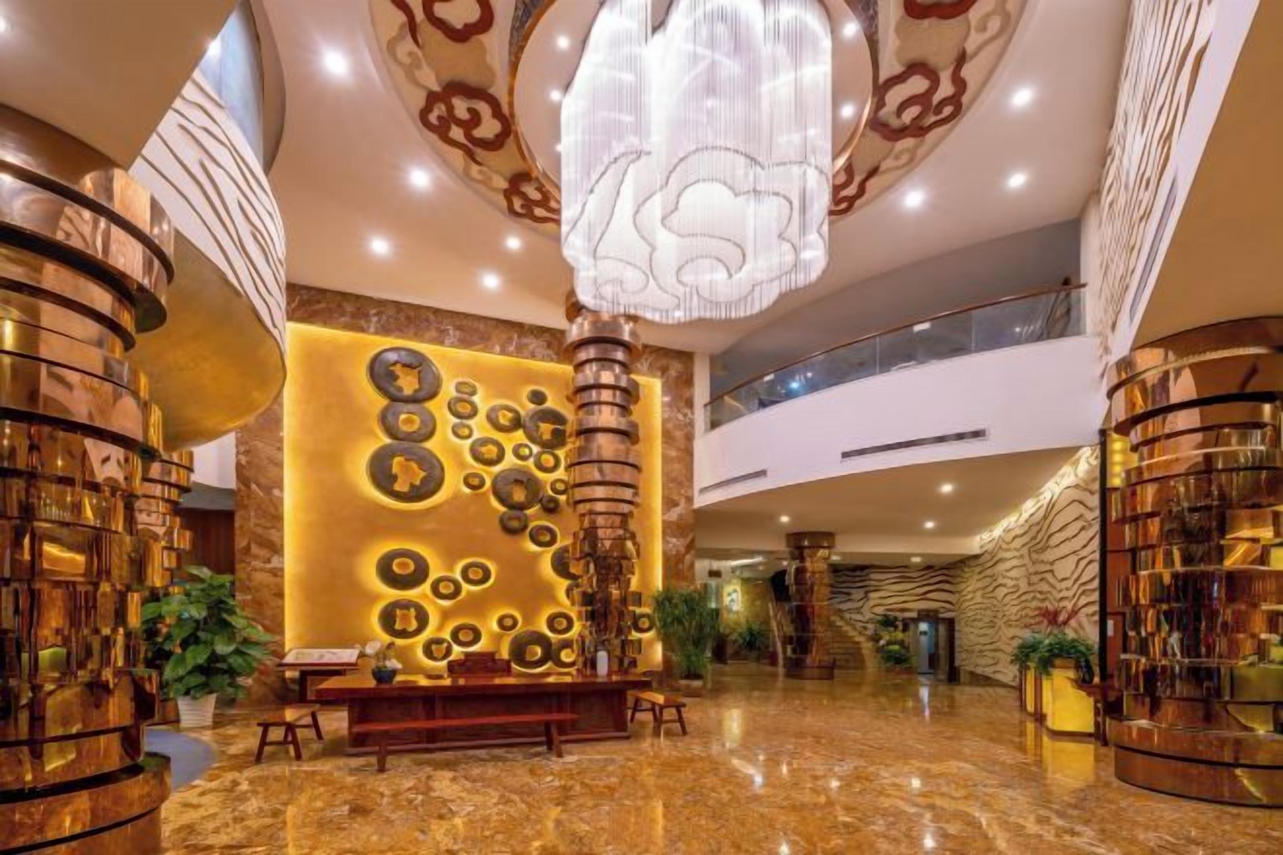 Un vestíbulo con mostrador de recepción, una gran pared decorativa y una escalera.