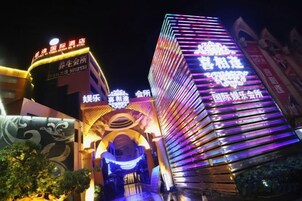 Fachada luminosa de un hotel con señalización iluminada y una entrada destacada.
