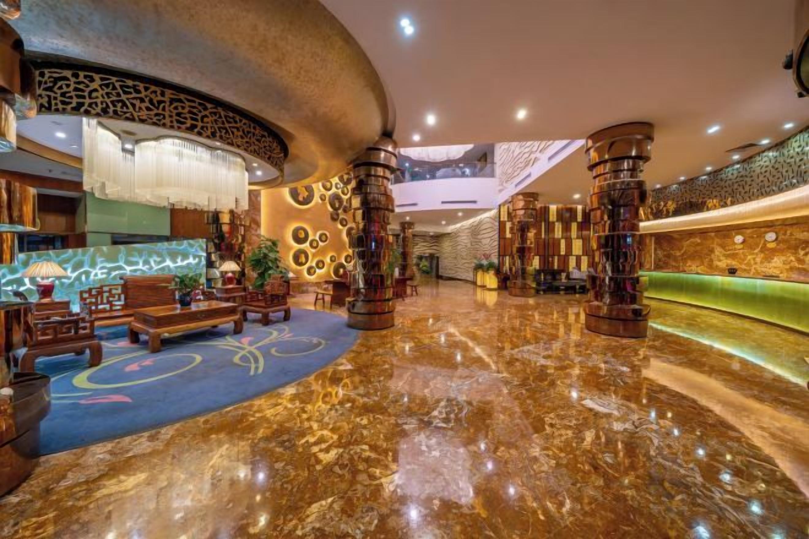 A lobby with a marble floor, a reception desk, and a seating area with a patterned carpet.