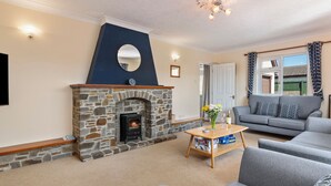A living room with a stone fireplace, grey sofas, a wooden coffee table, and a ceiling light fixture.