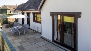 A patio with outdoor seating and a sliding glass door leading to a bedroom.