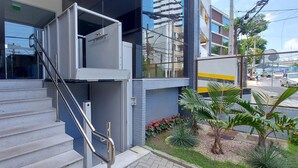 Un edificio moderno con una escalera, una puerta de vidrio y un pequeño jardín con plantas.