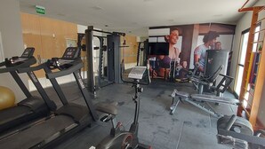 Un gimnasio con cintas de correr, máquinas de pesas y un espejo grande.