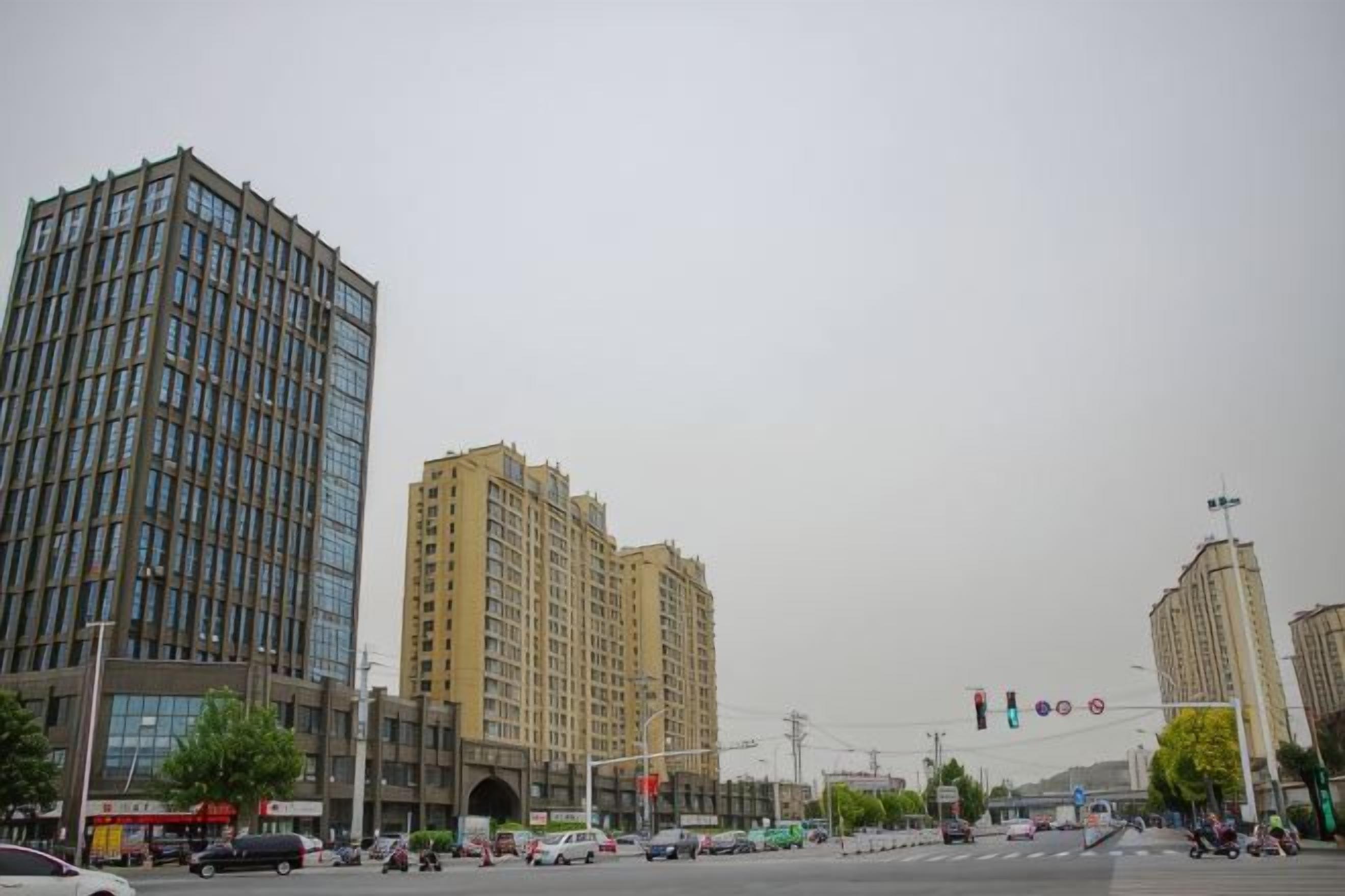 A cityscape with tall buildings, a traffic light, and a pedestrian crossing.