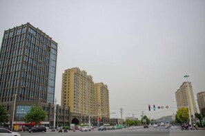Un paisaje urbano con edificios altos, un semáforo y un paso de peatones.