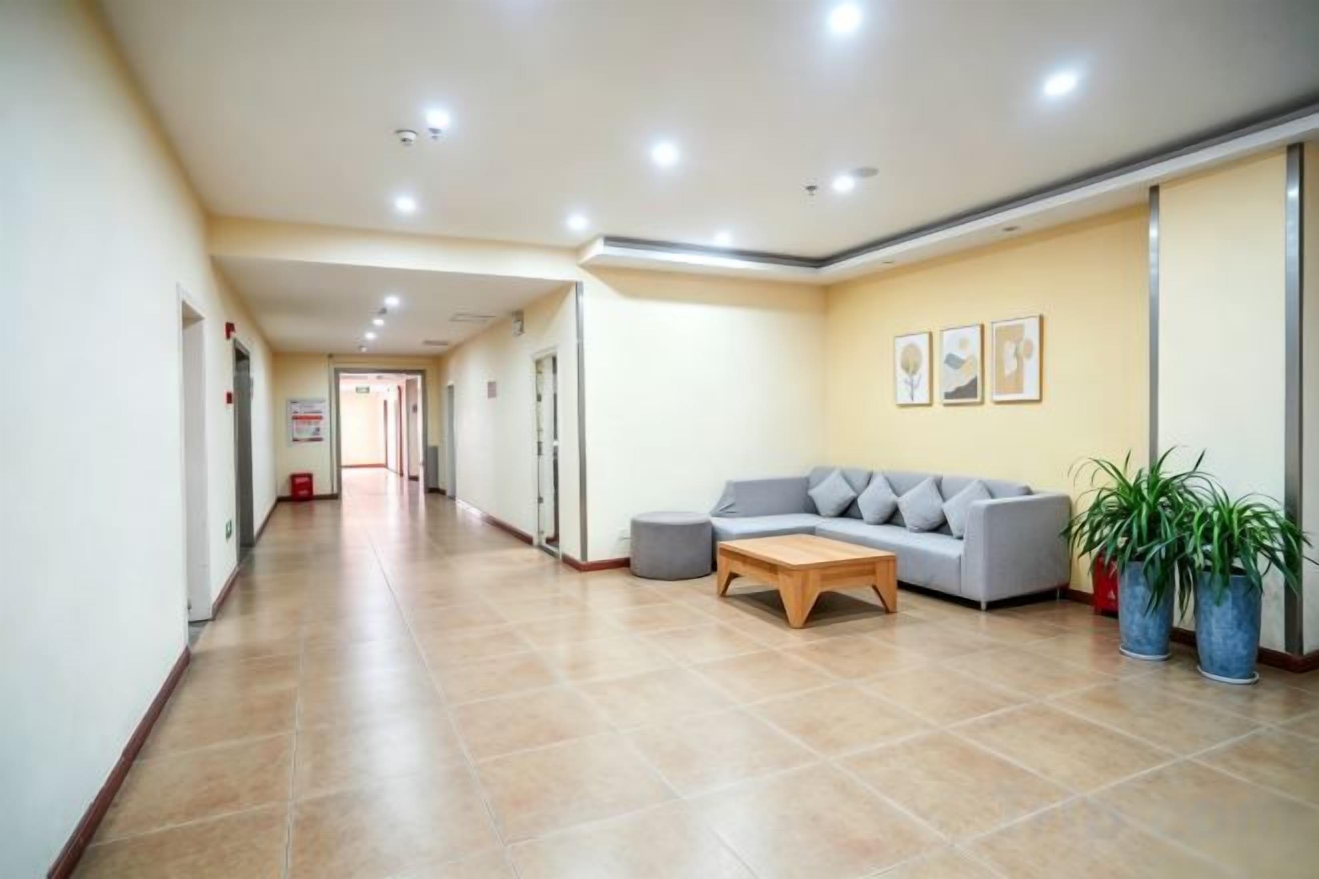 A hotel lobby with a reception desk, a sofa, and potted plants.