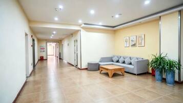 A hotel lobby with a reception desk, a sofa, and potted plants.