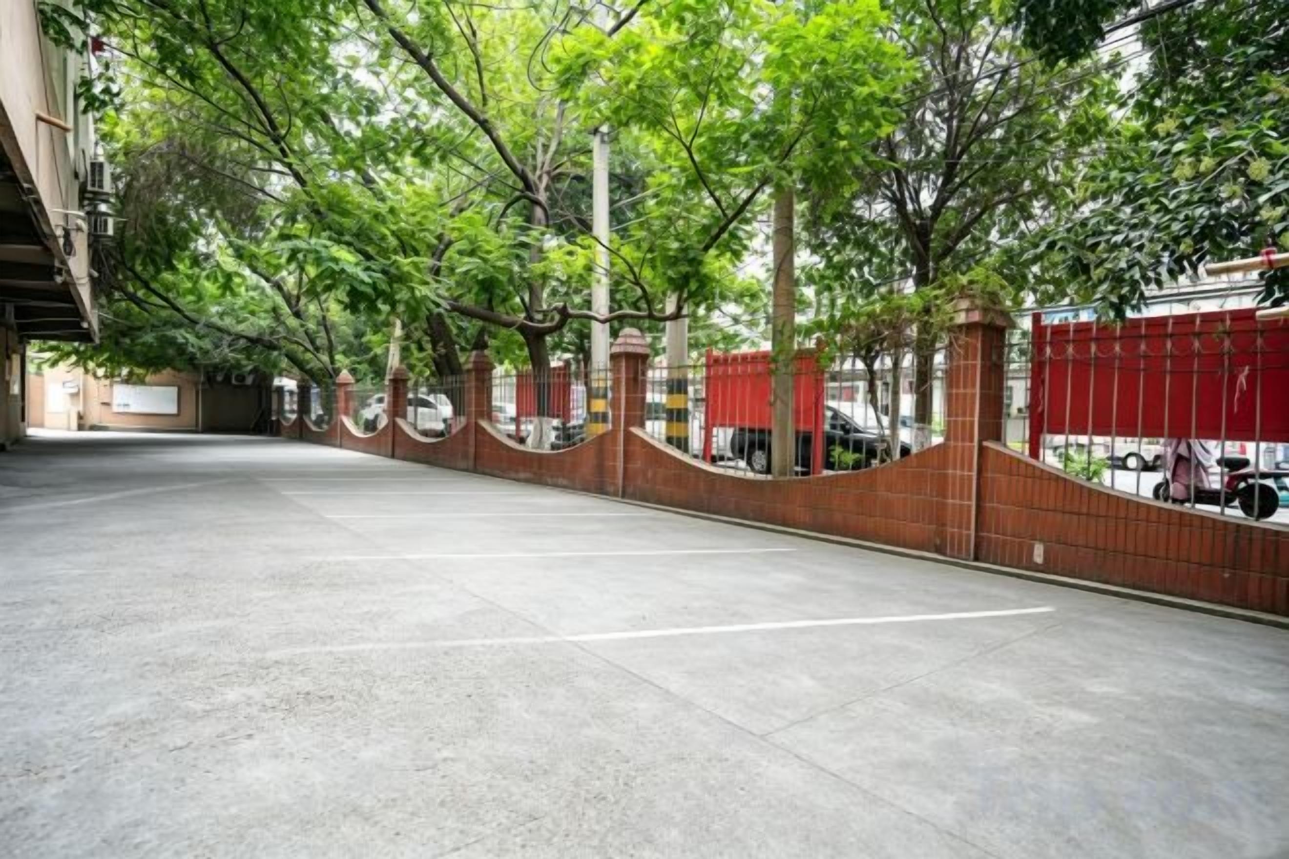 A parking area with a brick wall and trees.