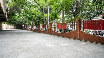A parking area with a brick wall and trees.